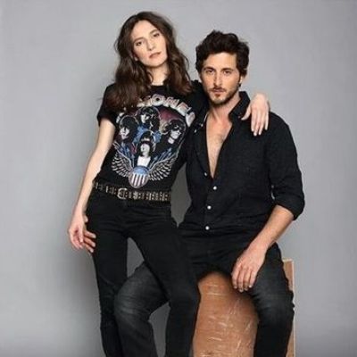 Tomer Capone is sitting on as Ortal Ben-Shoshan is holding onto him as they are wearing all black in the picture.